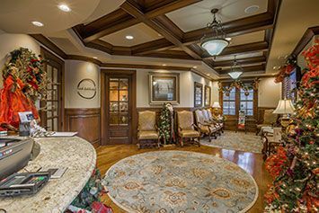A waiting room decorated for christmas with a round rug and christmas trees.