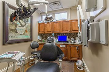A dental office with a dental chair and a painting on the wall.