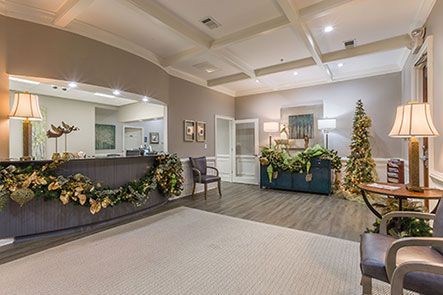 A lobby with a desk , chairs , lamps and a christmas tree.