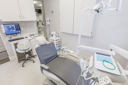 A dental office with a dental chair and a computer.