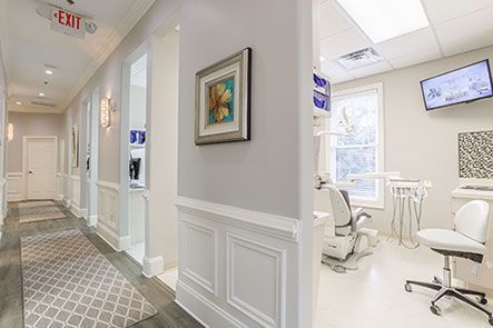 A long hallway leading to a dental office with a painting on the wall.