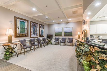 A large dental waiting room with a lot of chairs and lamps.