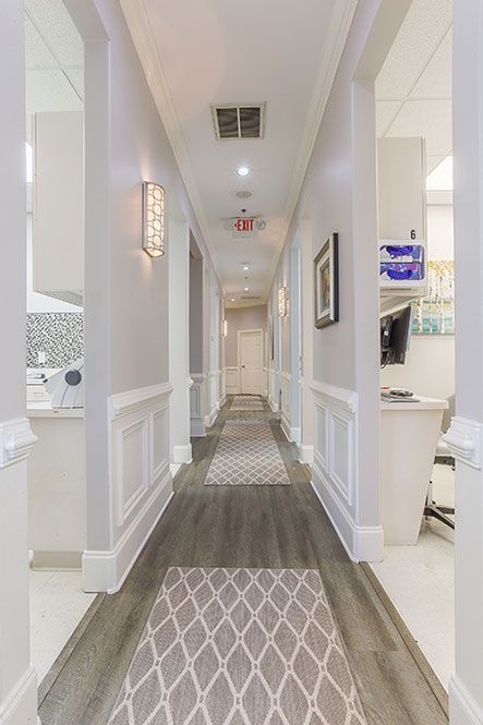 A long hallway in a dental office with a rug on the floor.