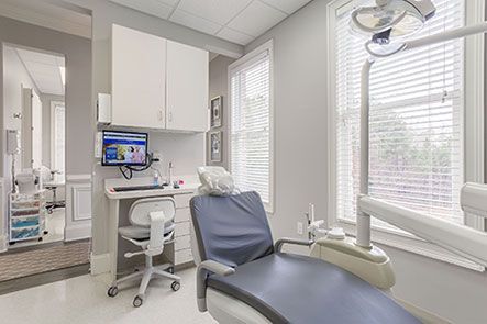 A dental office with a dental chair , desk and computer.