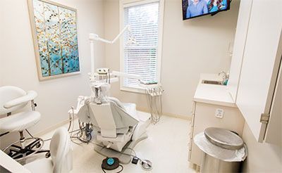 A dental office with a dental chair and a television on the wall.