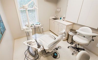 A dental office with a dental chair and a sink.