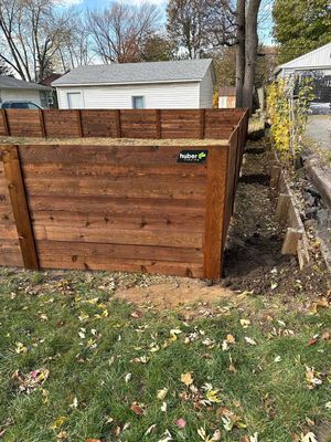 Wooden retaining wall in a backyard setting; a house and some trees are in the background.