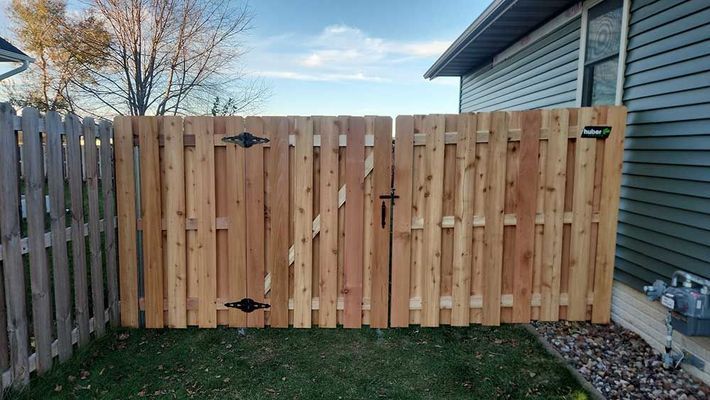 Wooden fence and gate in a yard, cedar planks, black hardware.