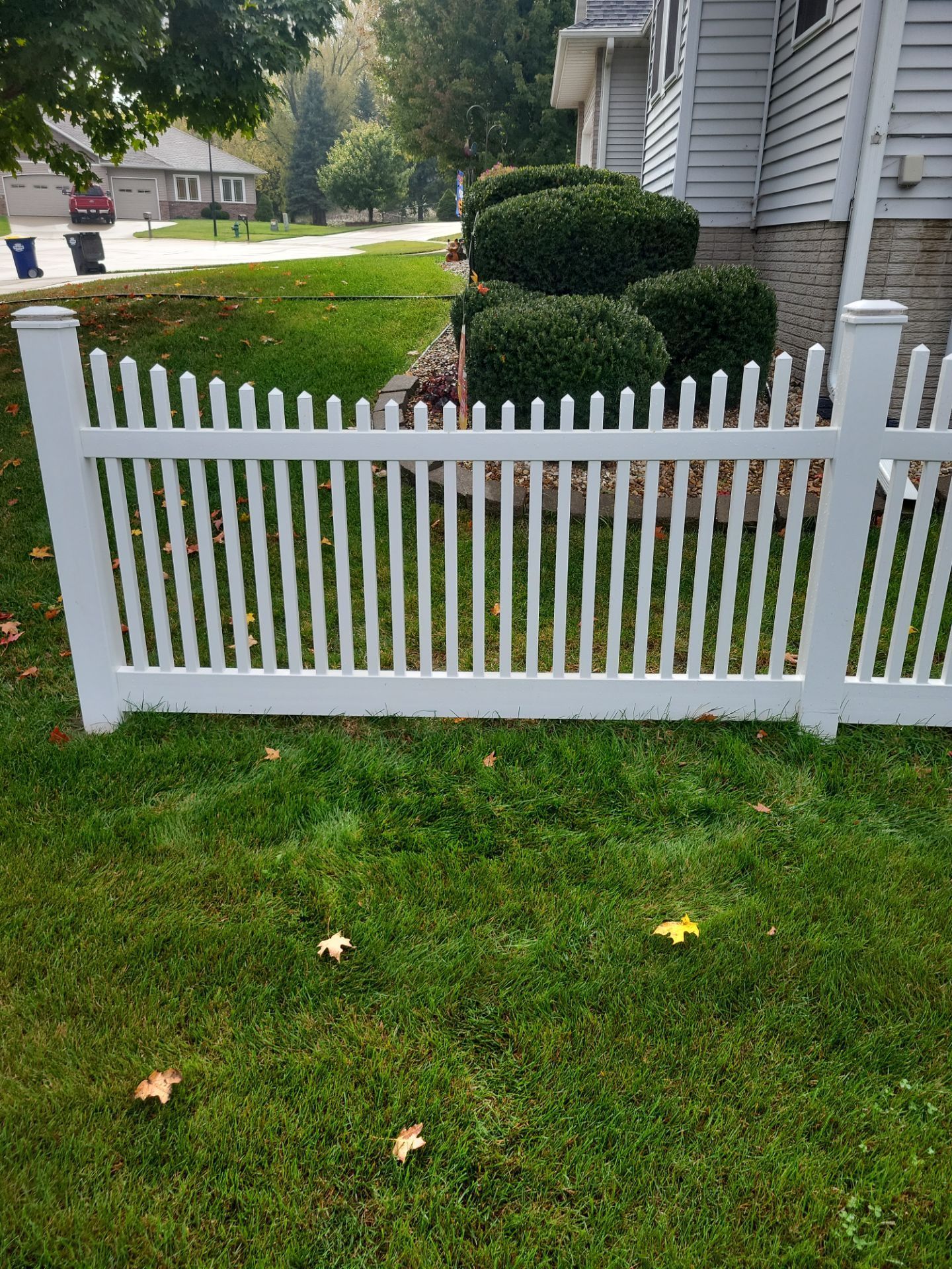 White picket fence bordering a green lawn in front of a house.