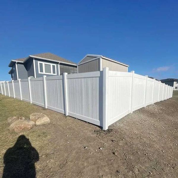 White vinyl fence surrounding a residential property on a sunny day.