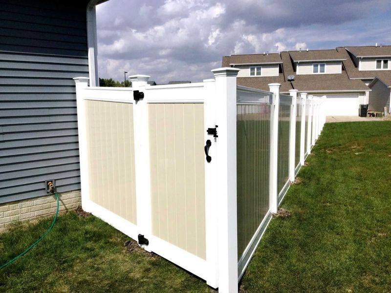 White vinyl fence and gate with beige panels in front of a house.