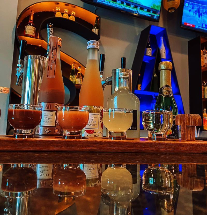 Bottles and glasses of liquor on a bar with a letter a in the background