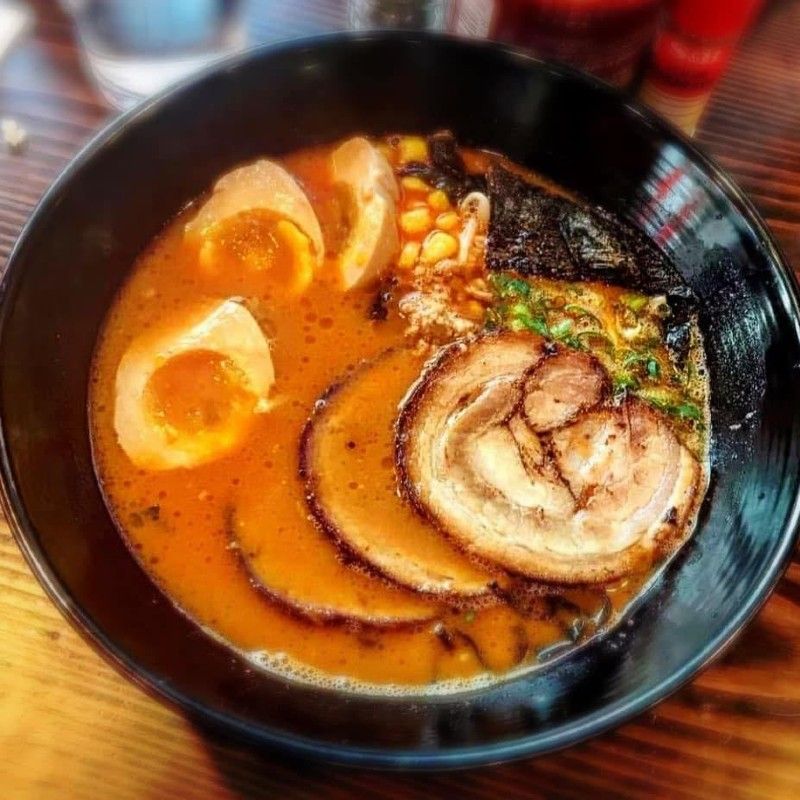 A bowl of soup with meat and eggs in it