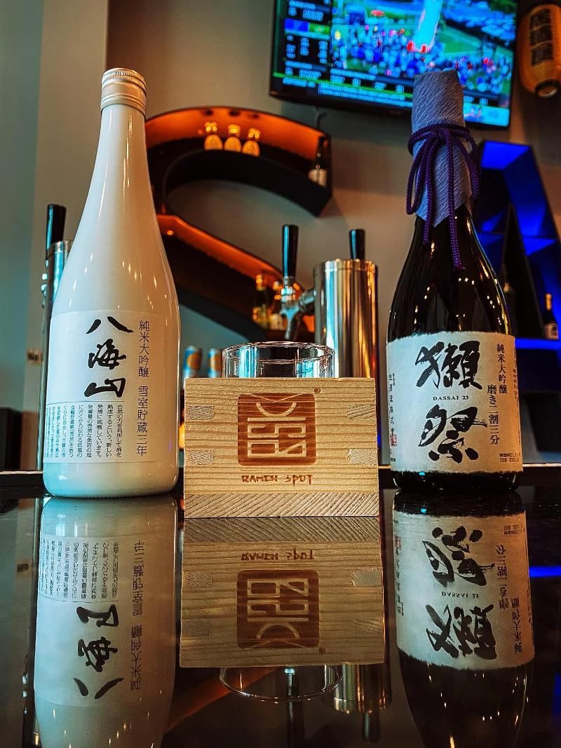 Two bottles of alcohol with chinese writing on them are sitting on a bar.