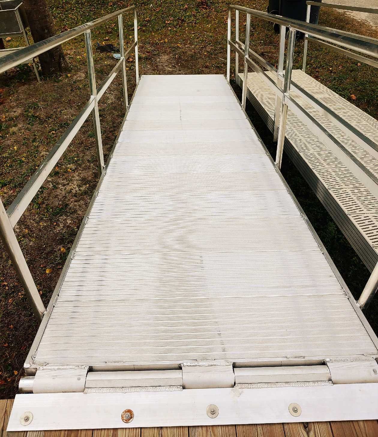 A white ramp with a metal railing on the side of it.