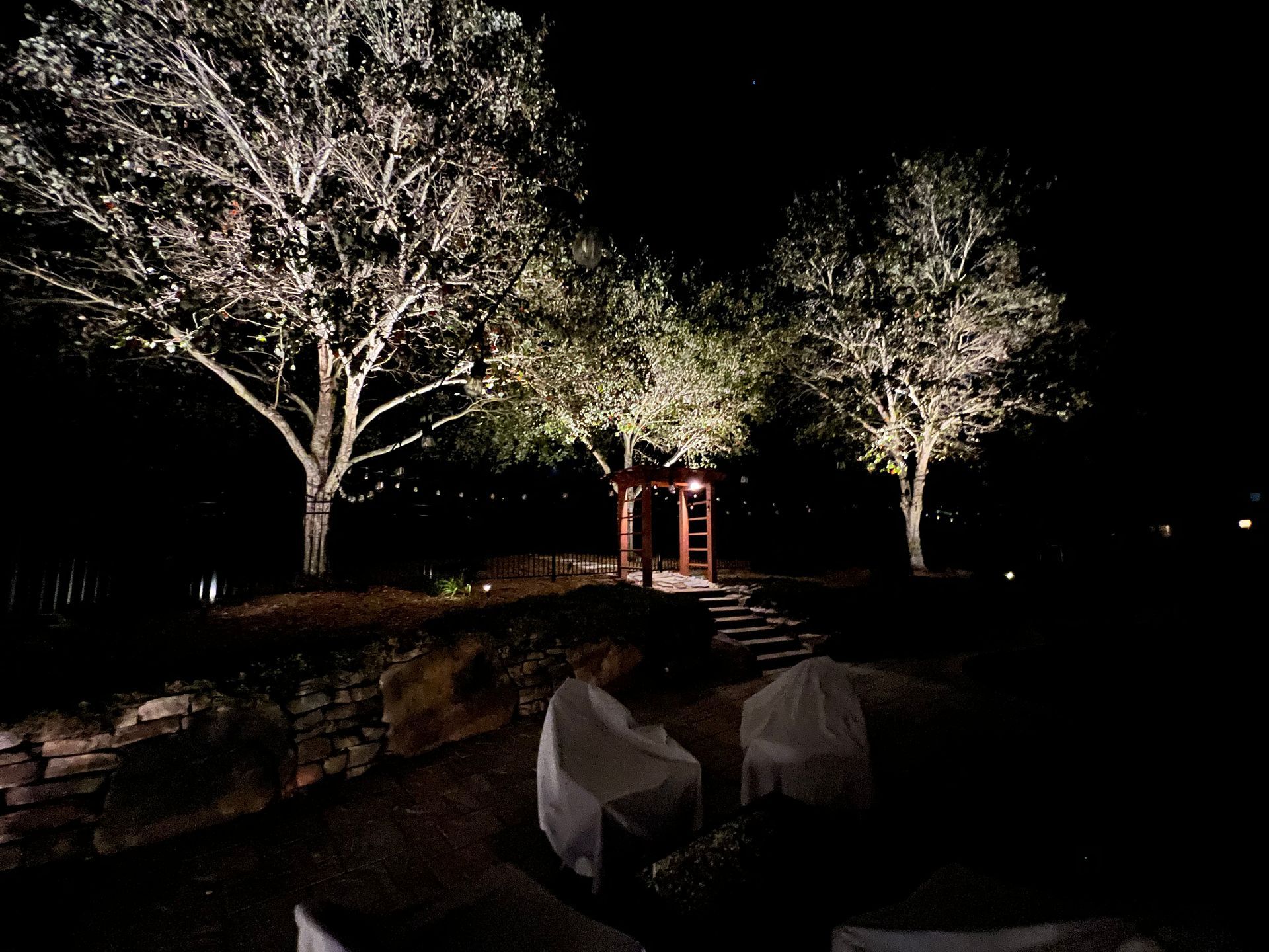 A tree house is lit up at night in a backyard.