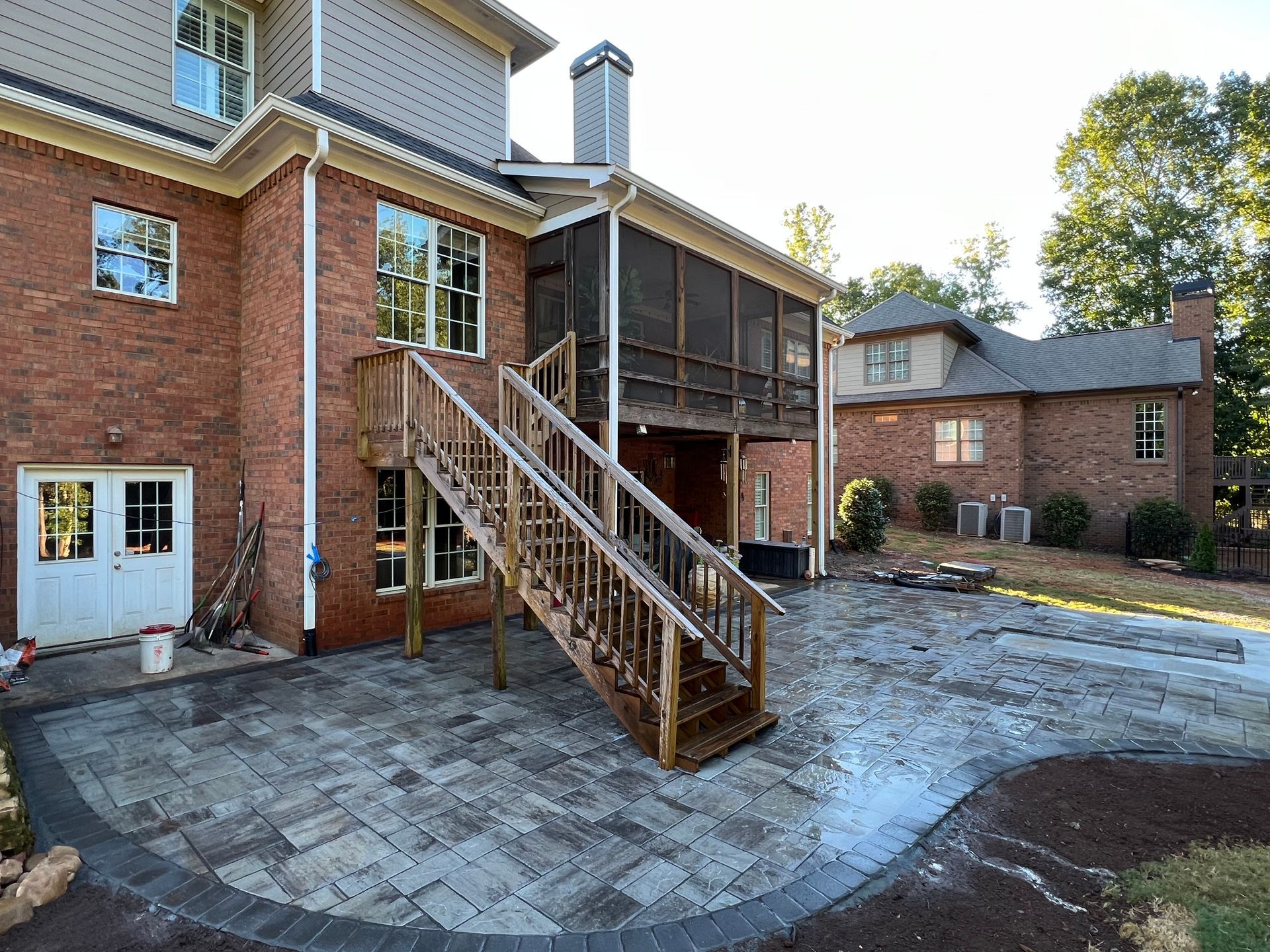 A large brick house with a screened in porch and stairs leading up to it.