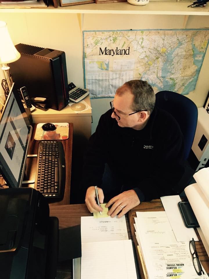 A man is sitting at a desk in front of a map of maryland