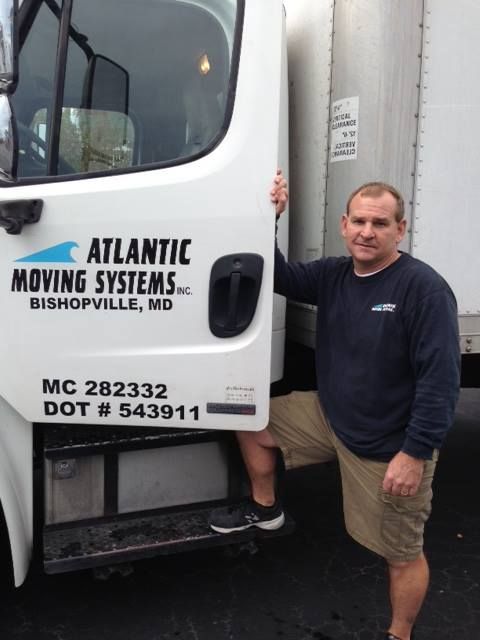 A man standing in front of an atlantic moving systems truck