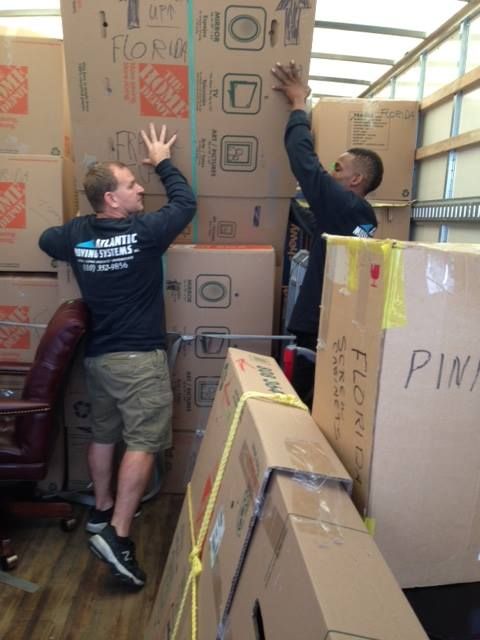 Two men are moving boxes in a home depot truck