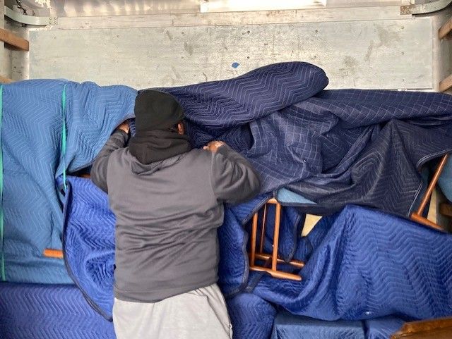A man is laying on a couch in a truck covered in blue blankets.