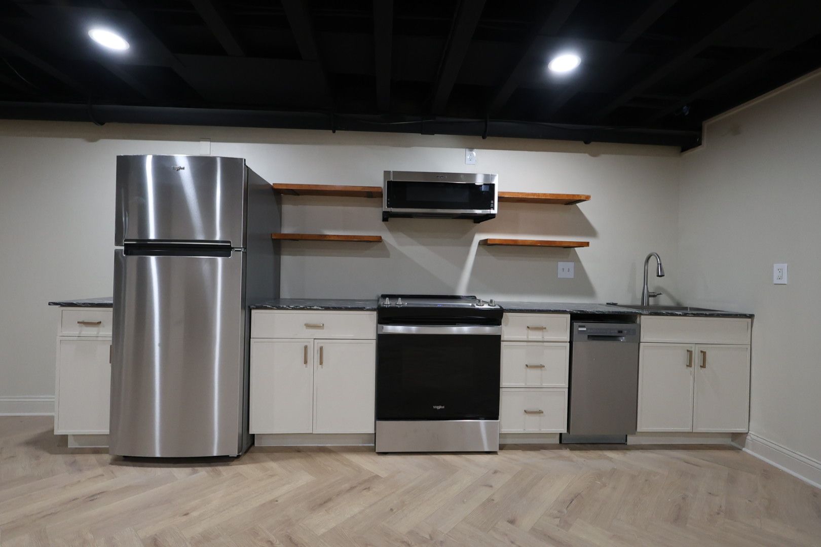 Modern kitchen with stainless steel appliances, white cabinets, wood shelves, and a black ceiling
