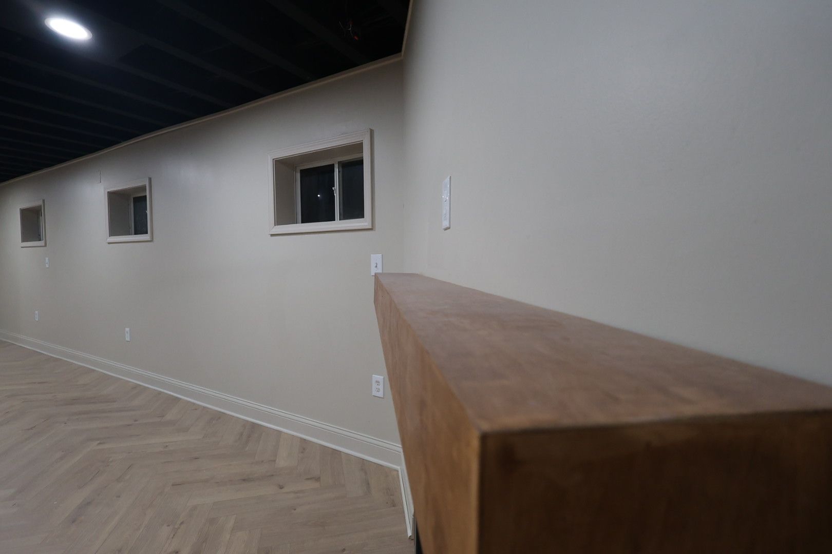 Empty hallway with white walls, small windows, and a wooden counter in the foreground