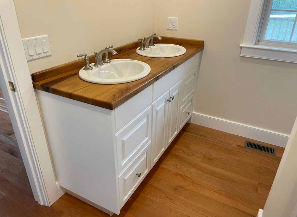 A bathroom with two sinks and a wooden counter top.