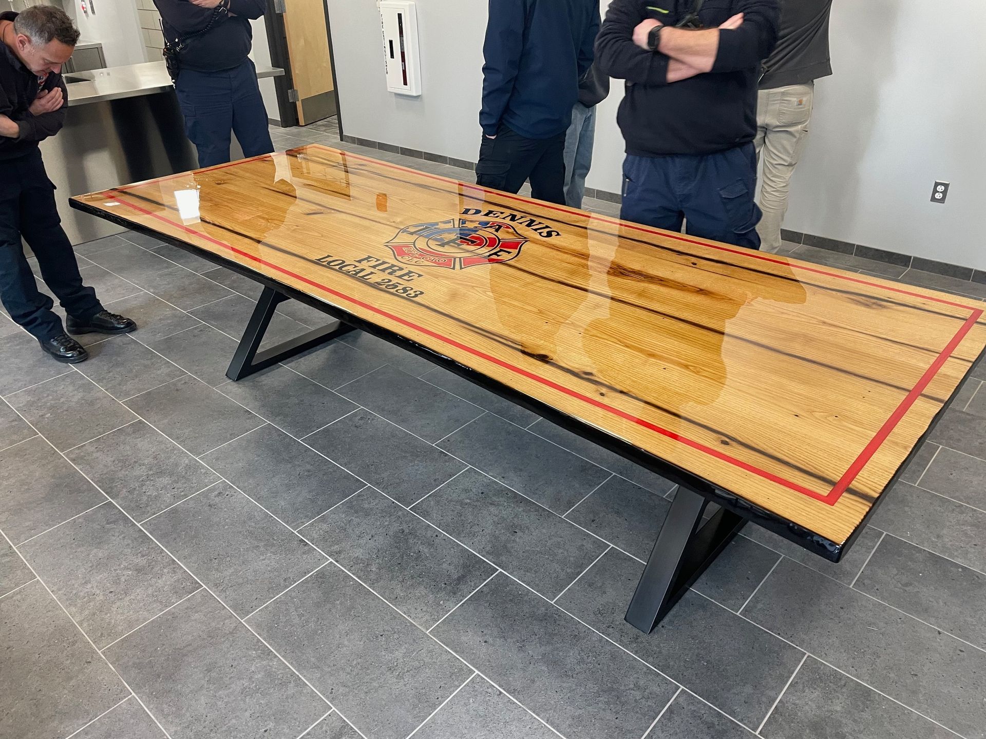 A group of men are standing around a long wooden table