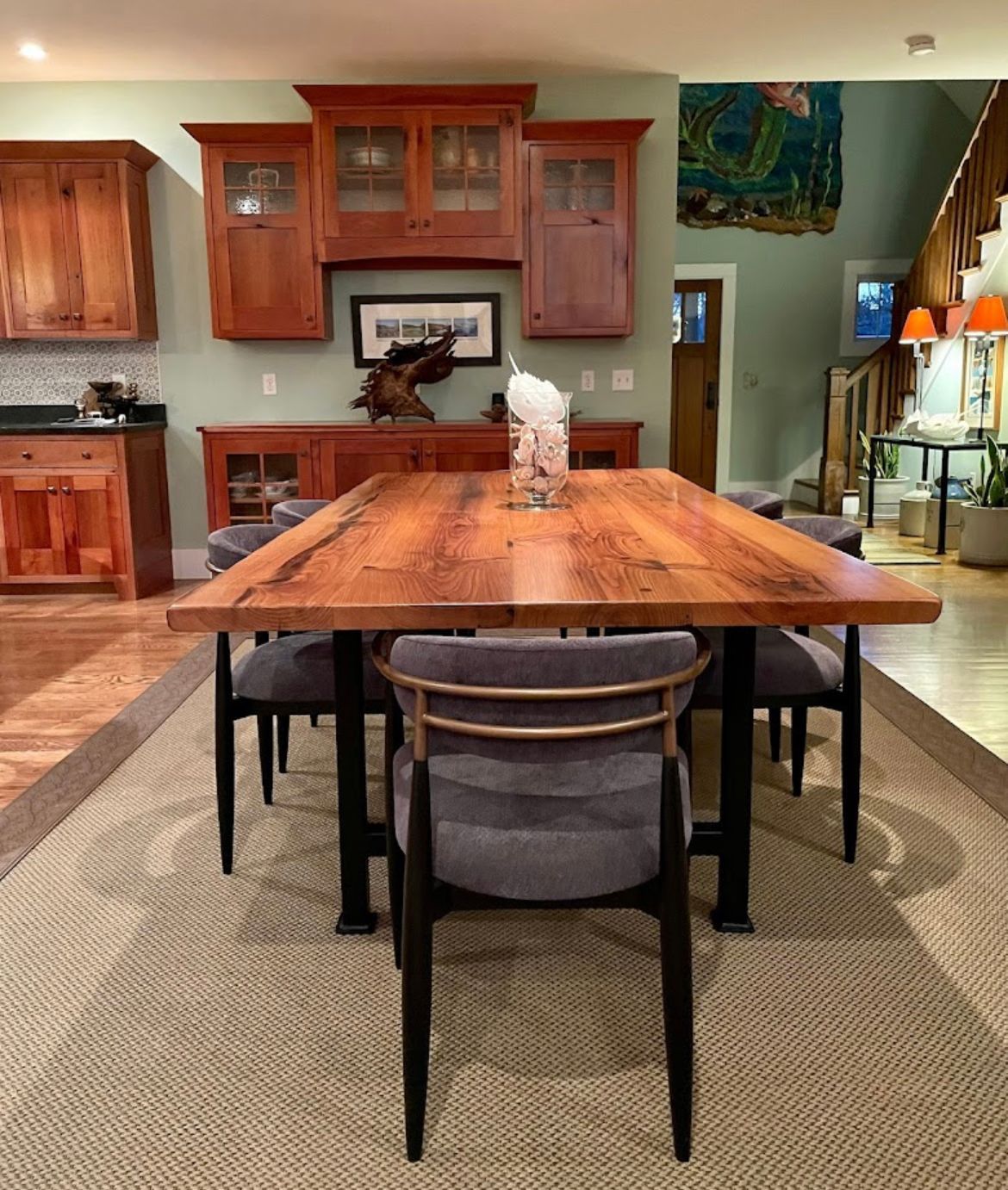A dining room with a wooden table and chairs and a rug.