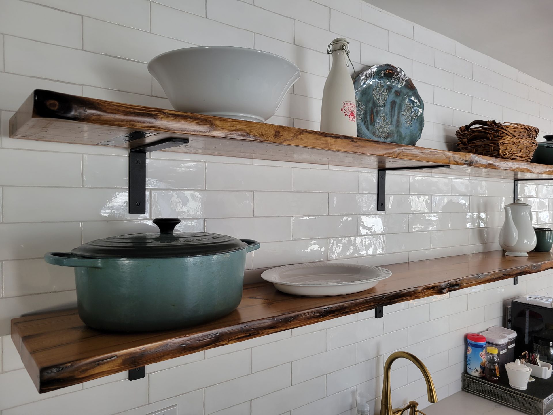 A kitchen with two wooden shelves filled with pots and pans.