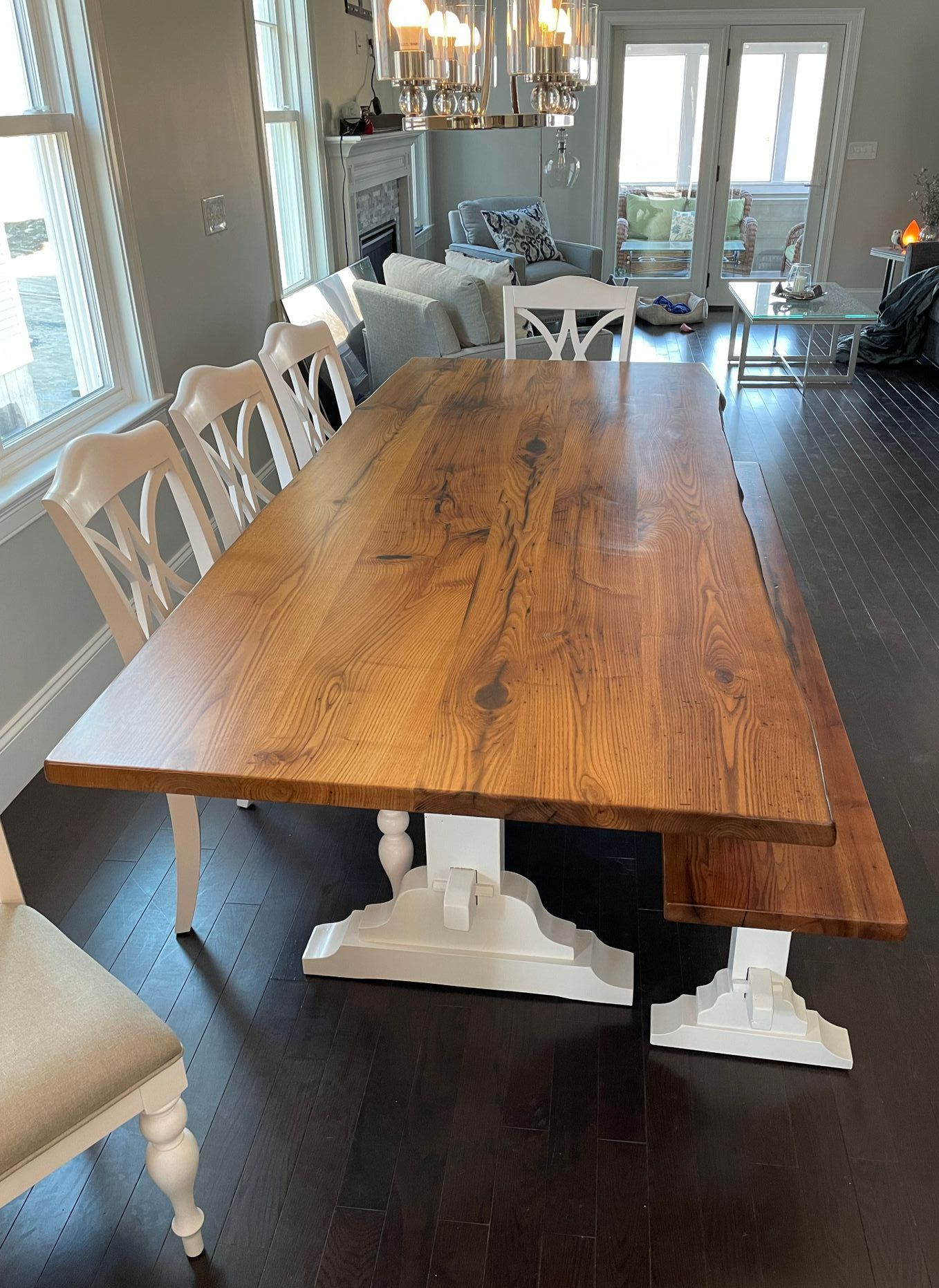 A wooden dining table with white chairs in a living room.