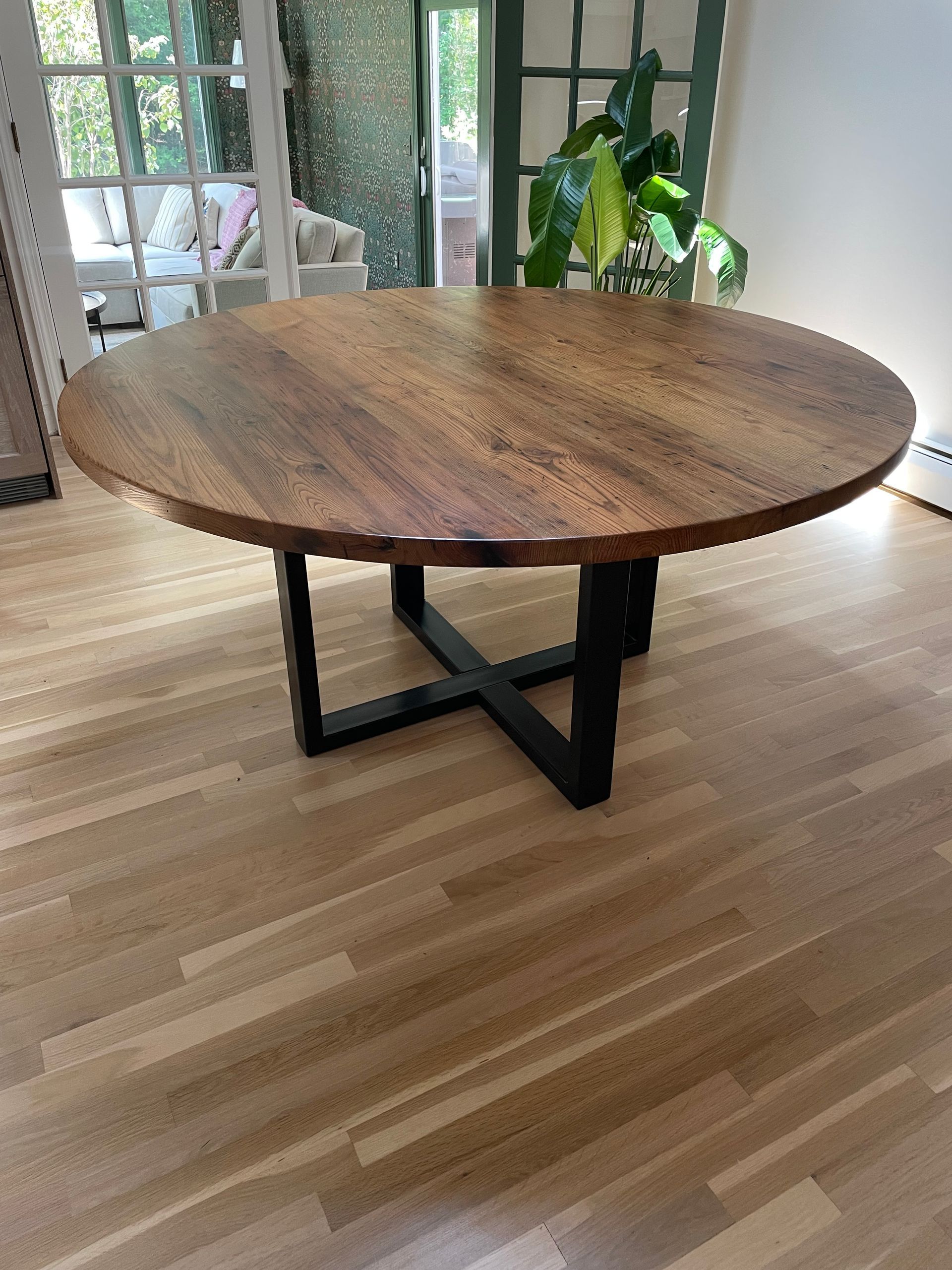 A round wooden table is sitting on a wooden floor in a living room.