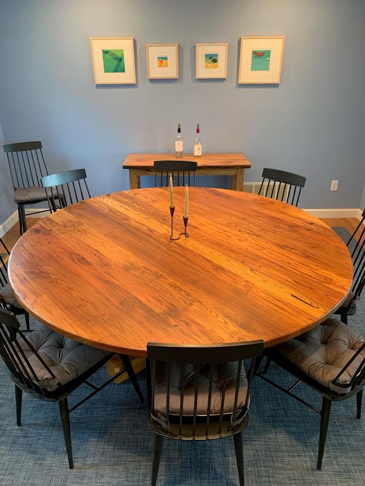 A dining room with a round wooden table and chairs
