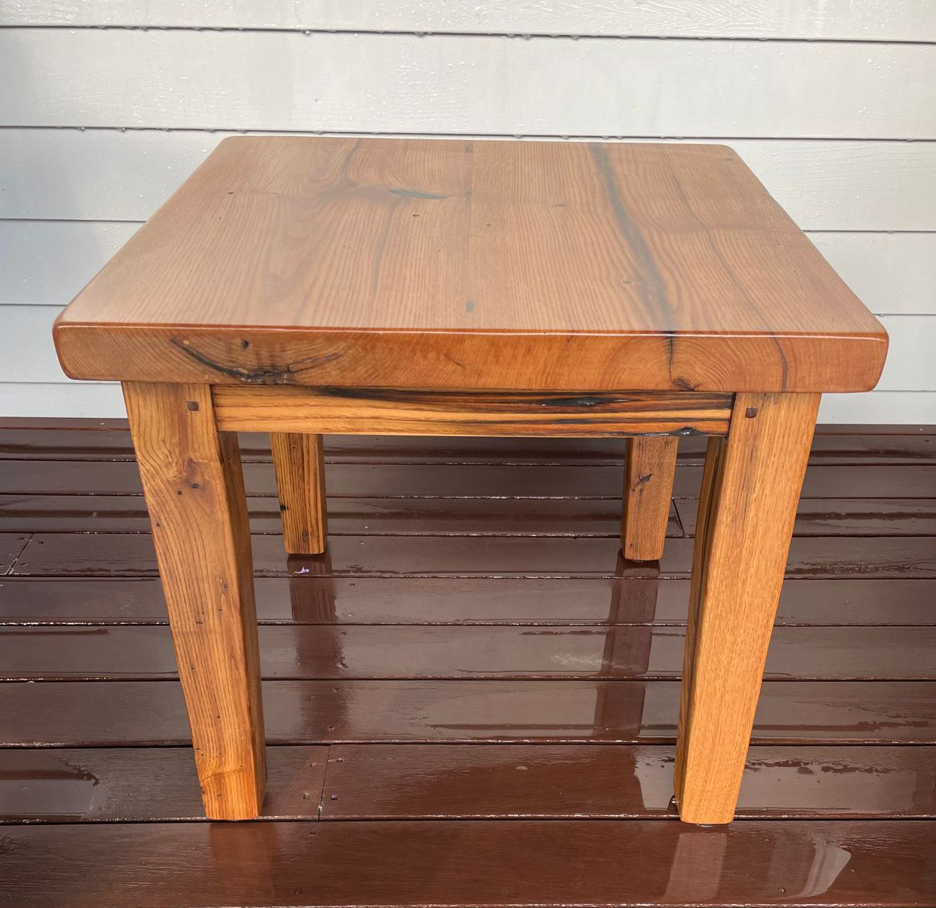 A small wooden table is sitting on a wooden deck