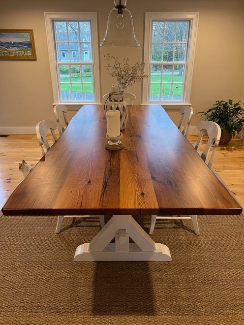 A dining room table with a vase of flowers on top of it.
