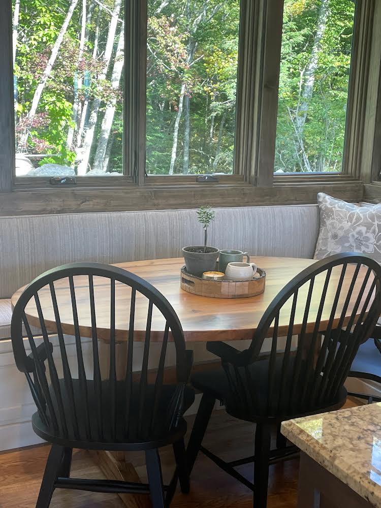 A dining room with a table and chairs in front of a window.