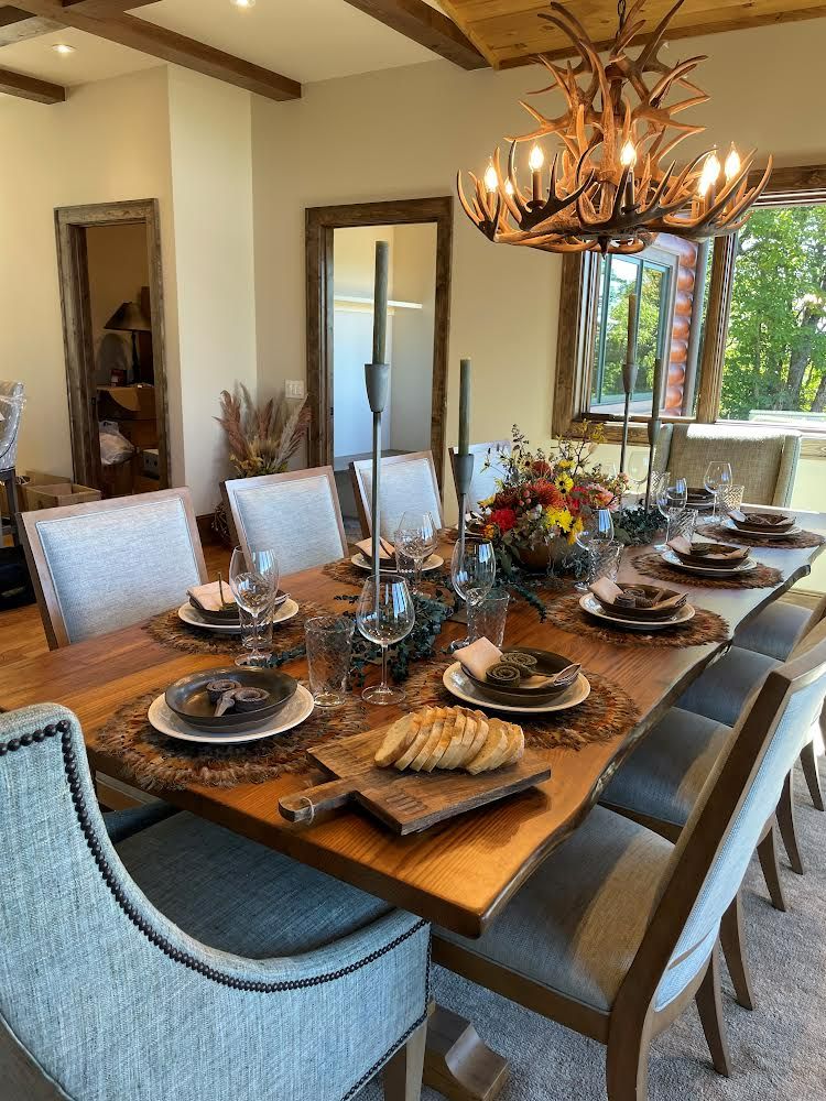 A dining room table with plates and chairs and a chandelier.