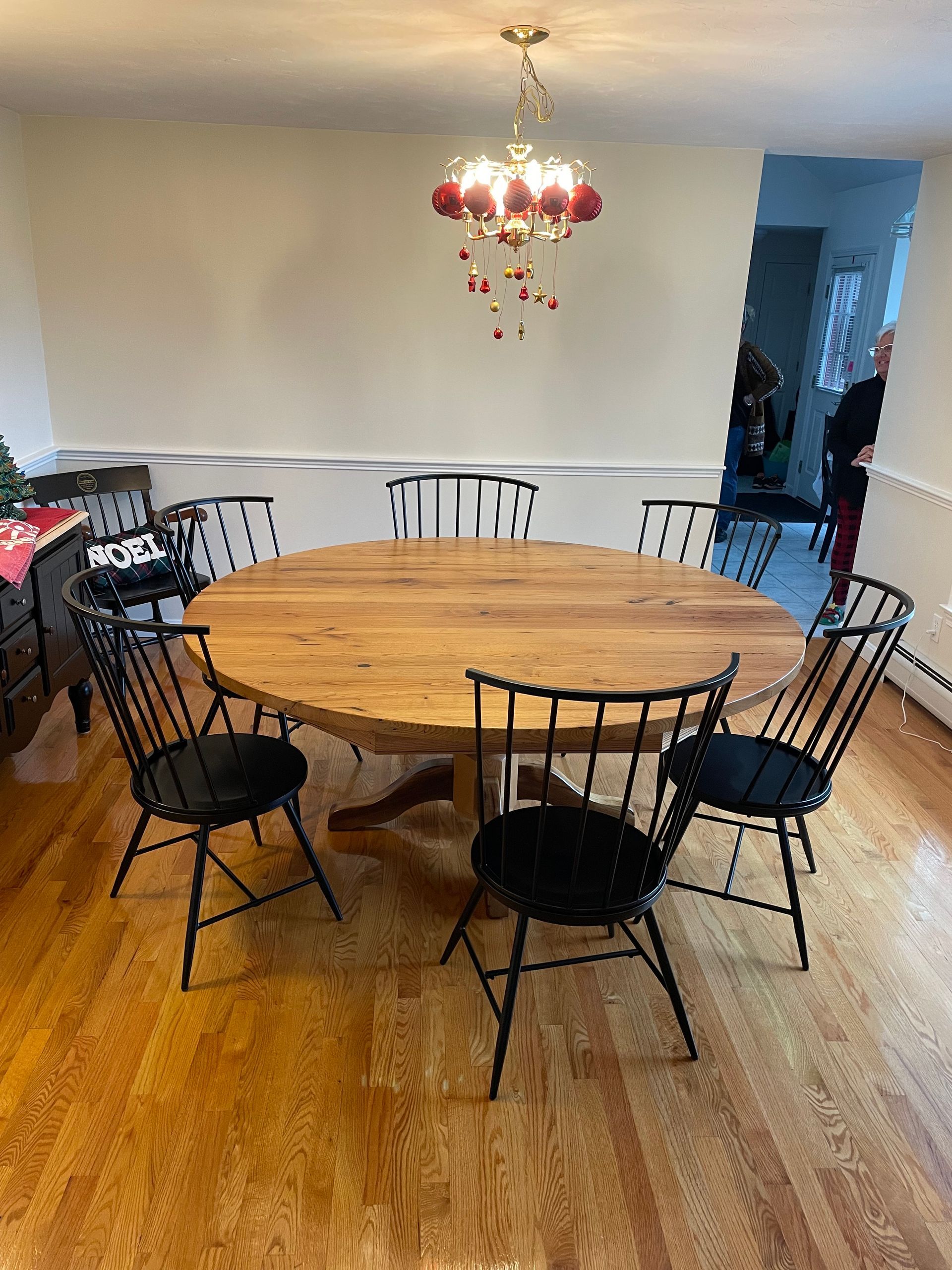 A round wooden table with black chairs in a dining room.