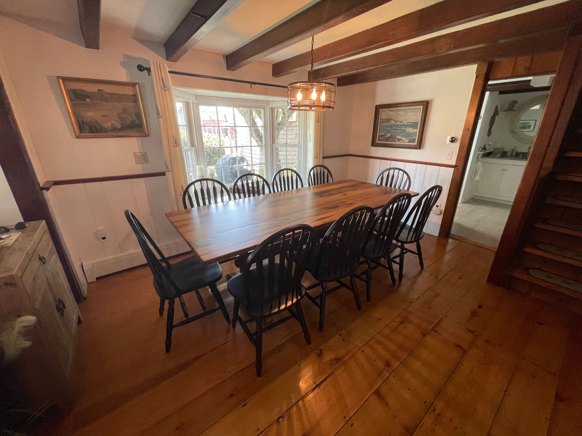 A dining room with a long wooden table and chairs.