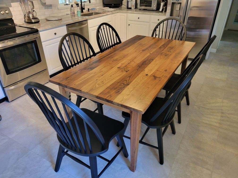 A wooden table with black chairs in a kitchen.