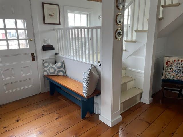 A wooden bench in a hallway next to a staircase.