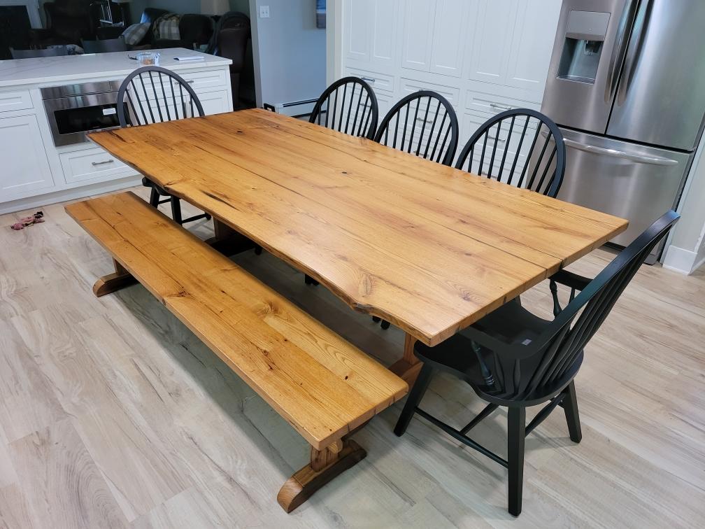 A wooden table with a bench and chairs in a kitchen.