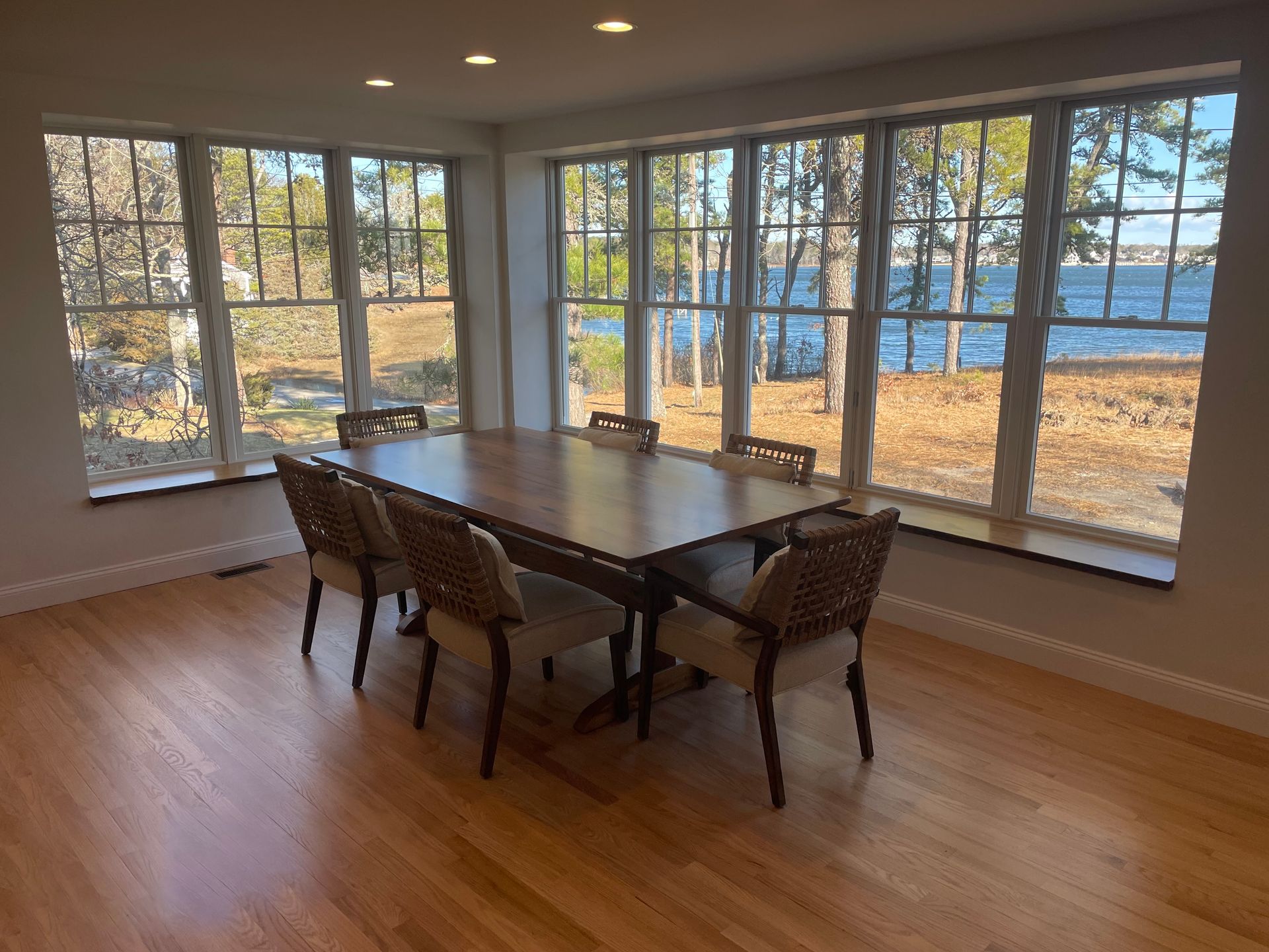 A dining room with a table and chairs and a lot of windows.