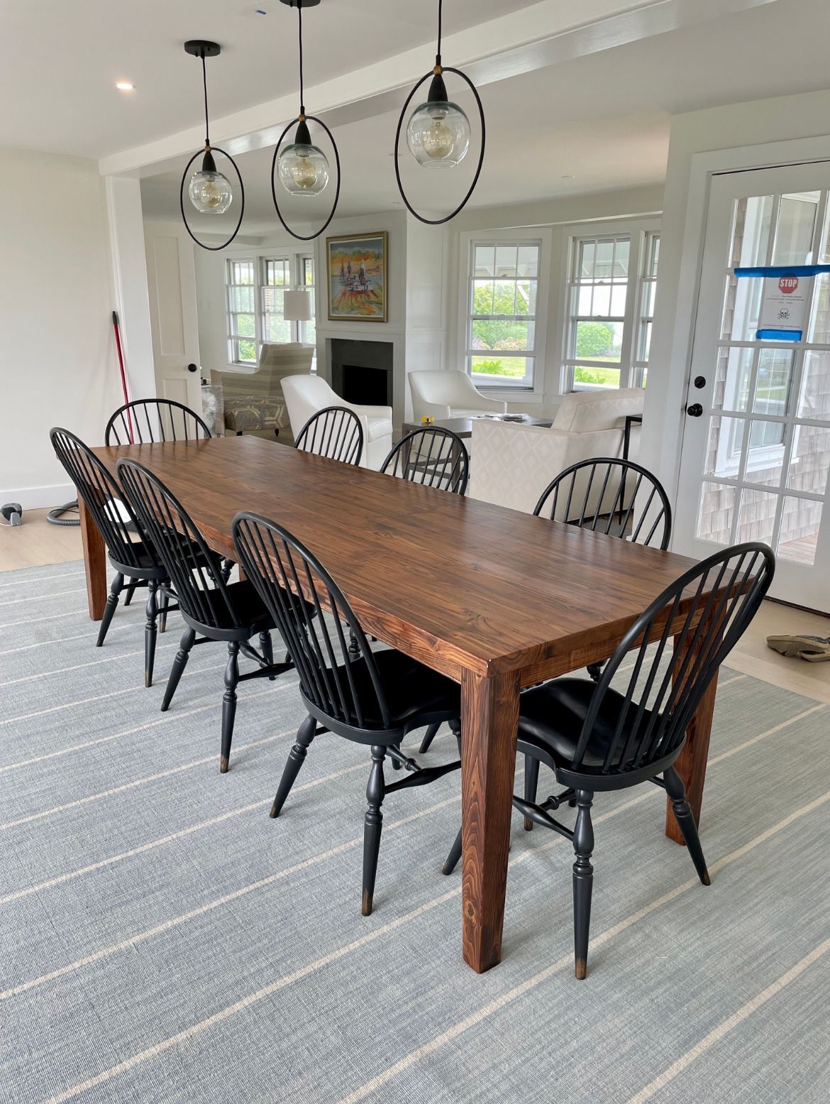 A long wooden dining table with black chairs in a living room.