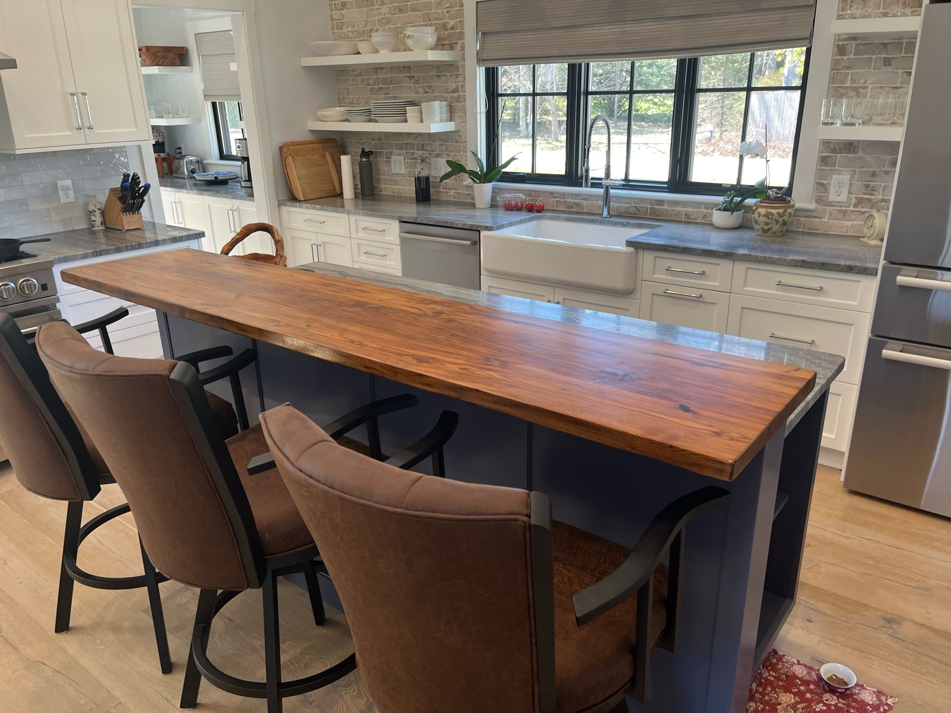 A kitchen with a wooden counter top and chairs.