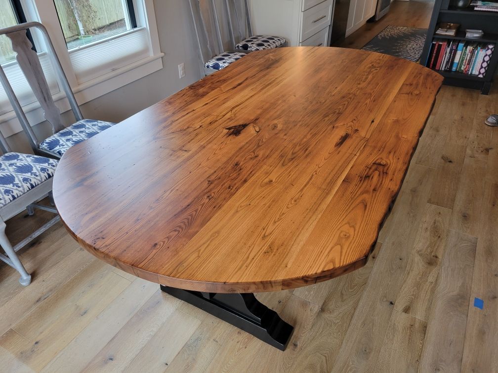 A wooden table with a round top is sitting on a wooden floor in a living room.