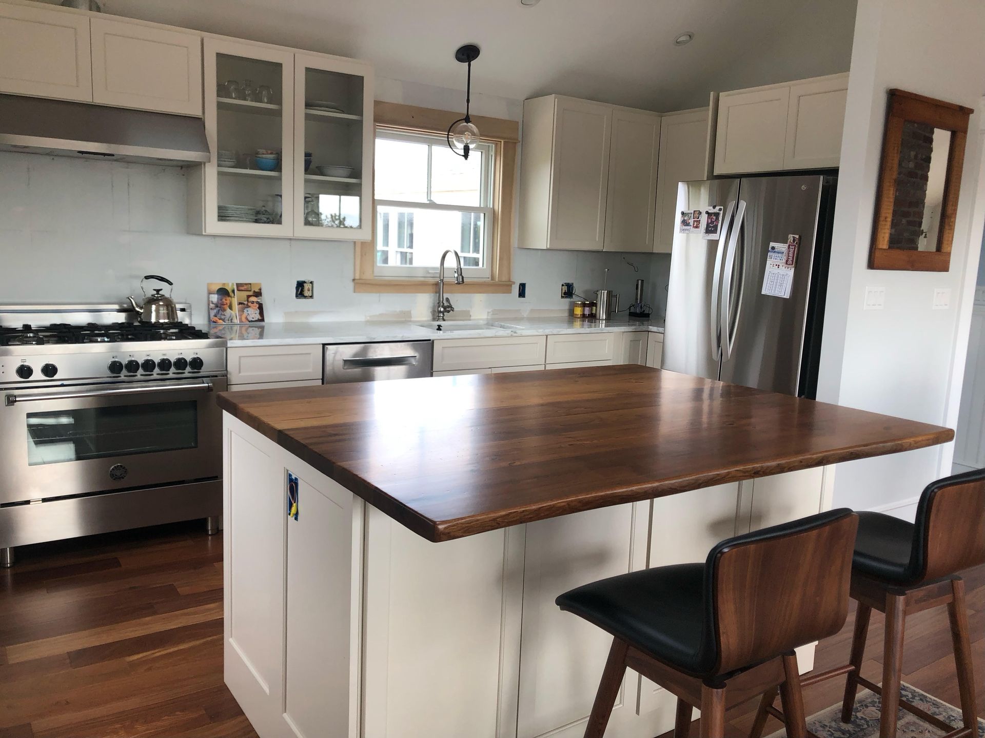 A kitchen with white cabinets and a wooden counter top