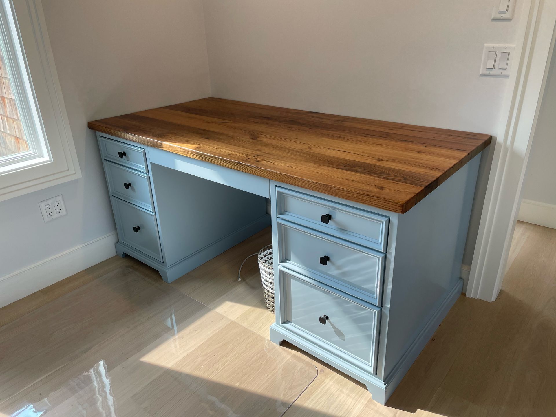 A light blue desk with a wooden top and drawers in a room.
