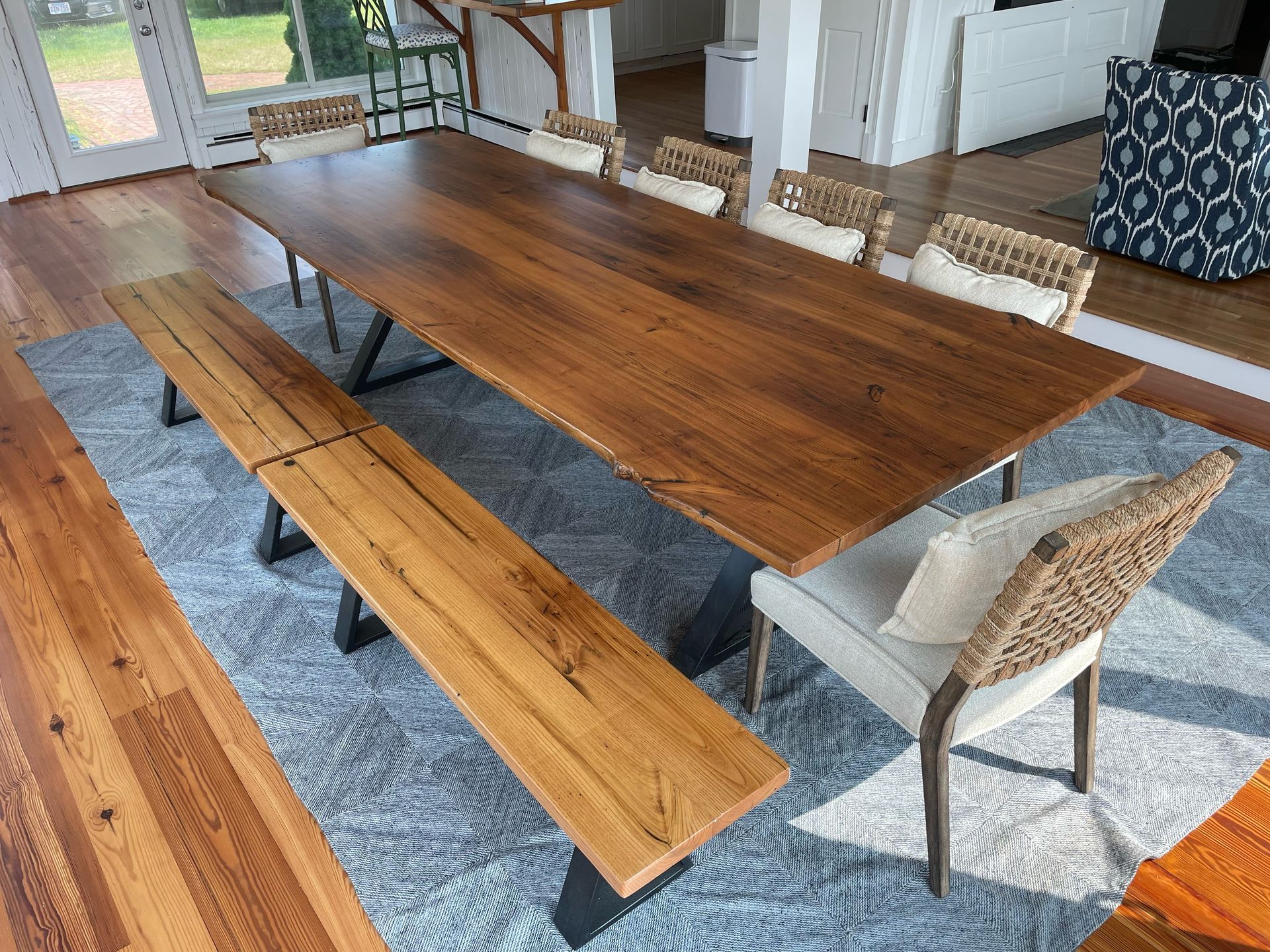 A wooden dining table with a bench and chairs in a living room.